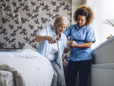 caregiver assisting elder woman in standing up concept