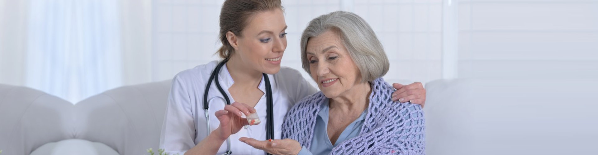 caregiver giving elder woman medicine